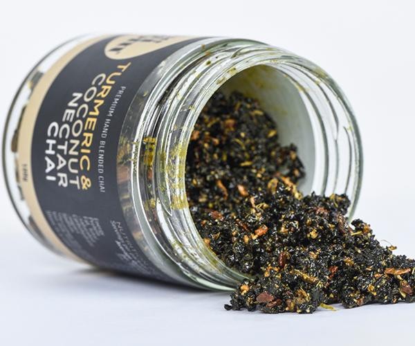 An open jar of turmeric & Coconut Nectar Chai lying on its side and pouring out of the jar so you can see much of the ingredients